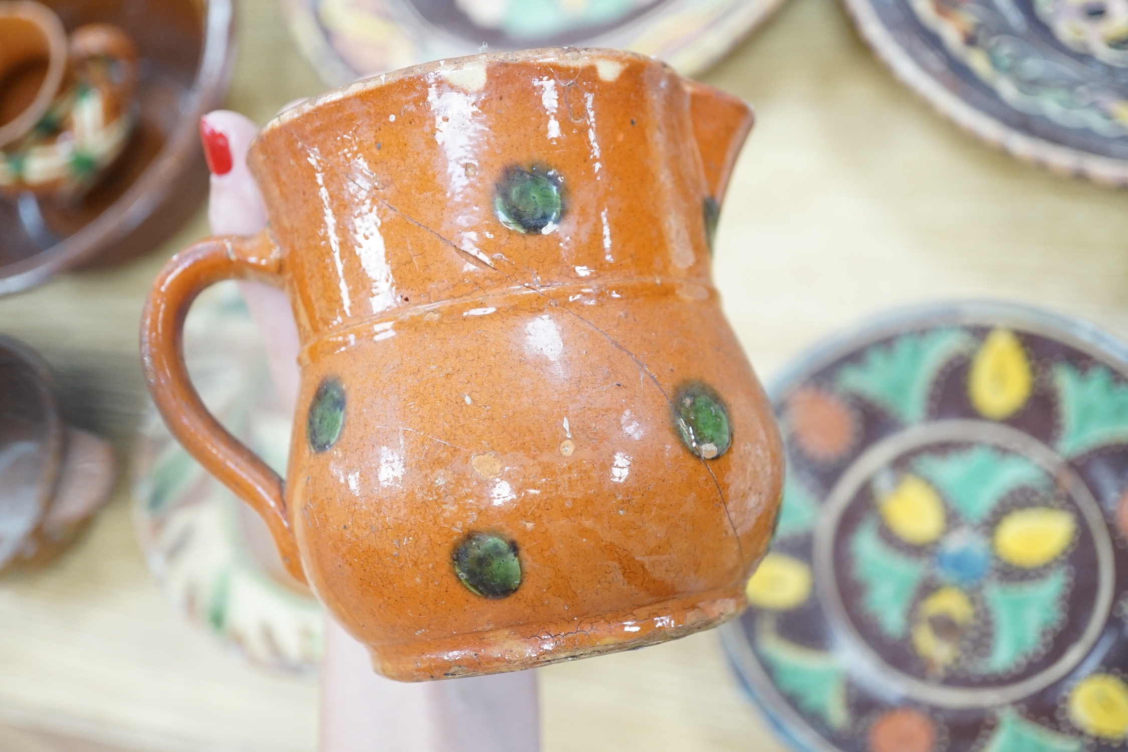 A group of Mediterranean slipware dishes, bowls and jugs, decorated in colours on a predominantly brown or ochre ground, the largest 33cm in diameter